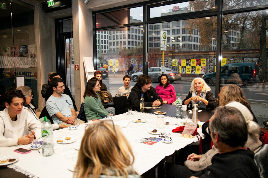 Personen sitzen an einem großen Tisch und sprechen miteinander
